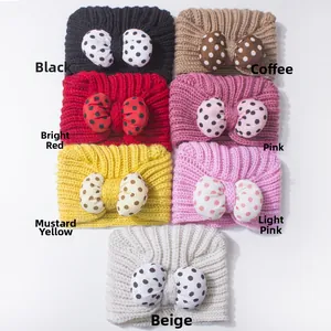 Flat lay of seven colorful knitted baby headbands with polka dot bows in various colors