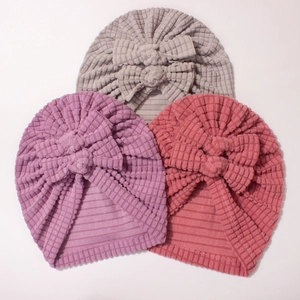 Close-up of three soft waffle knit baby turban hats with large bows in purple pink and gray