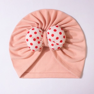 Detailed close-up of pink baby turban hat featuring a red and white polka dot bow tie