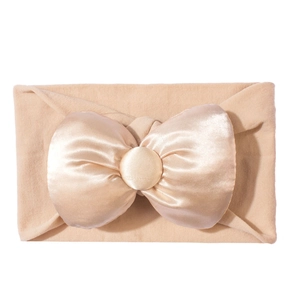 Detail eines rosa elastischen Baby-Stirnbandes mit großer Satinschleife und Knopf-Detail