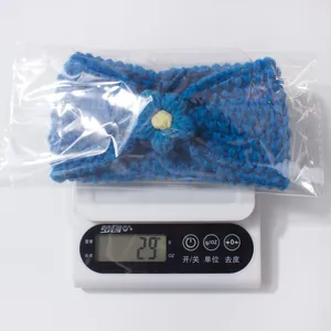 Detailed view of a handmade blue crochet flower headband on a scale weighing 29 grams