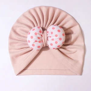 Detailed view of baby turban hat with a large pink polka dot bow and pleated fabric