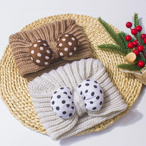 Cute knitted baby headbands with polka dot bows in coffee and cream on a rustic tray
