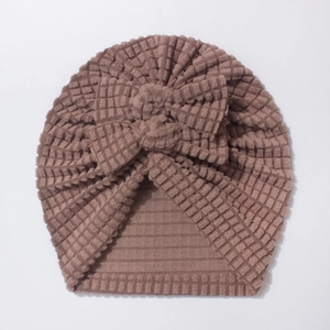 Detail of baby beanie featuring waffle texture fabric and a large decorative bow