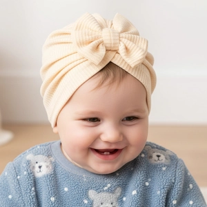 Détail macro du bonnet turban beige en maille gaufrée pour bébé avec un grand nœud doux