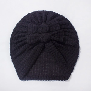 Close-up of black waffle-knit baby turban hat with a triple-layered decorative bow