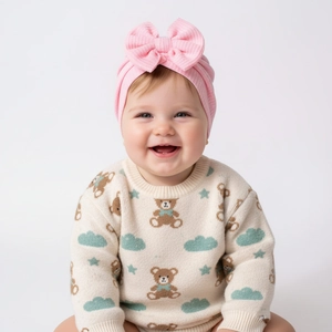 Détail d'un turban bébé rose avec noeud et pull en tricot avec motif d'ours