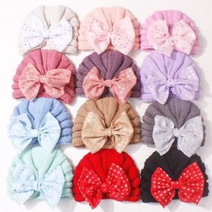 Flat lay of twelve ribbed baby knit beanies with metallic star print bows in various colors