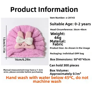 Pink knitted baby hat with rabbit ears detail showing size measurements for ages 0-2 years