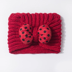 Detail view of a red baby knit headband featuring a large 3D polka dot bow decoration