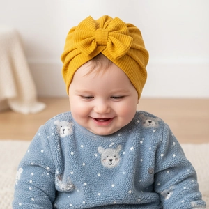 Gros plan d'un bonnet gaufré jaune vif pour bébé avec un grand nœud décoratif sur l'enfant