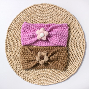 Detail of pink and brown knitted baby headbands with handmade flowers on straw mat