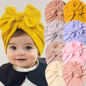 Détail de la texture gaufre et du grand nœud sur des bonnets turbans pour bébés