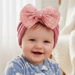 Detailed close-up of pink baby knitted hat with large sequined mesh bow decoration