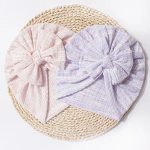 Dettaglio dei cappelli a turbante per neonati in maglia a nido d'ape rosa e viola