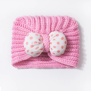 Close-up of pink knit baby headband with a large stuffed polka dot bow decoration