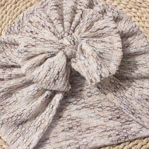 Dettaglio del cappello neonato in maglia a nido d'ape beige e marrone con fiocco