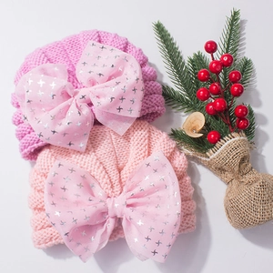 Detail of pink knitted baby hats with large mesh bows and silver star patterns