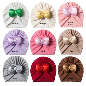 Vue en neuf couleurs de bonnets pour bébé avec grands nœuds en satin et textures