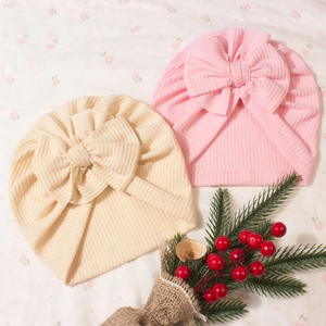 Détail de bonnets turban gaufrés pour bébé en beige et rose avec grands nœuds décoratifs