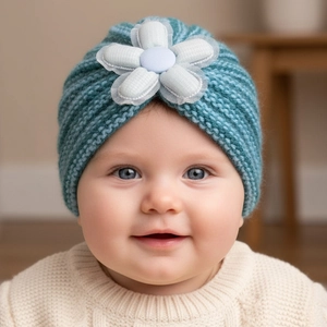 Detailed close-up of a blue striped knitted baby hat with a large floral decoration