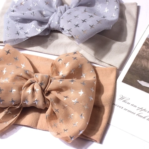 Détail de bandeaux bébé en nylon avec nœuds argentés imprimés en gris et abricot