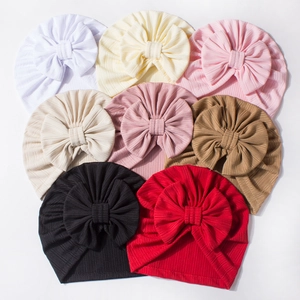 Flat lay of eight baby waffle turban hats with large decorative bows in various solid colors