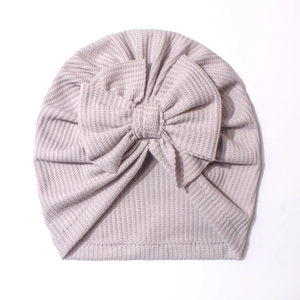 Détail du bonnet turban pour bébé en maille gaufrée rose avec un grand nœud