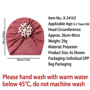 Pink baby turban hat with black polka dot flower design for infants aged 0-2 years