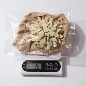 Vue détaillée d'un bonnet rayé marron pour bébé avec une grande fleur décorative en kaki