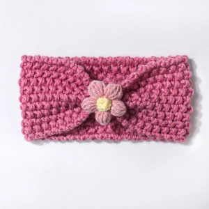 Close-up of soft crochet baby headband with pink handmade flower and knit texture