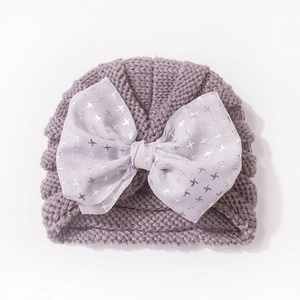 Detail of lavender knitted baby turban with a large silver printed bow for winter