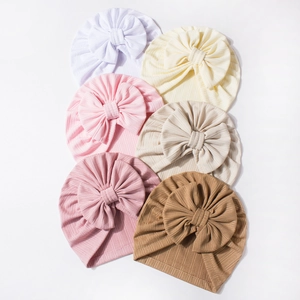 Close-up of six waffle knit baby turban hats with large bows in soft Morandi colors