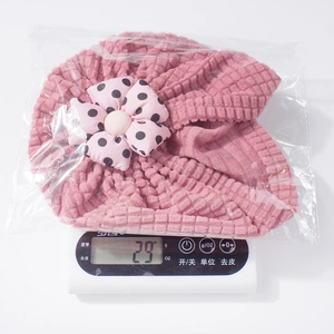 Detailed view of pink infant beanie with waffle texture and polka dot flower decoration