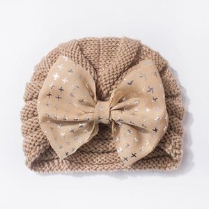 Detail of baby knitted hat in khaki with a large bow featuring silver star patterns