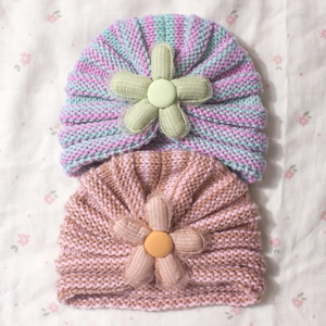 Detailed knit texture of baby hats with striped patterns and 3D fabric flowers