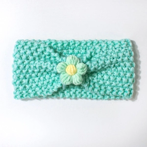 Detailed knit texture of mint green baby headband with central flower and yellow core