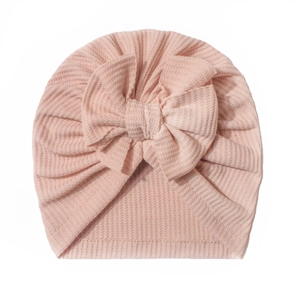 Détail du bonnet turban rose pour bébé en maille gaufrée avec grand nœud décoratif
