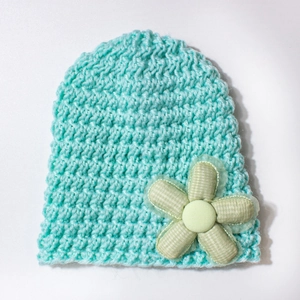 Close-up of mint green knitted baby hat featuring a 3D crochet flower detail