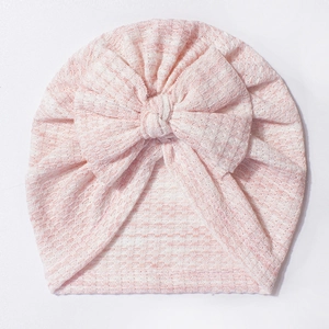 Dettaglio del cappello a turbante per neonati in maglia a nido d'ape rosa e bianco