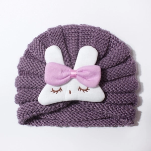 Detail of purple knitted baby turban hat with a cute plush rabbit and pink silk bow tie