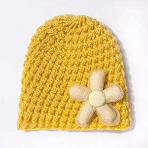 Close-up of yellow knitted baby hat with delicate handcrafted flower and thick texture