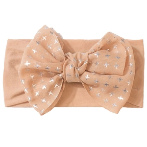 Détail d'un bandeau pour bébé en nylon avec un grand nœud champagne et motifs d'étoiles