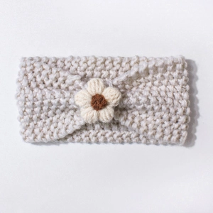 Detailed close-up of knit texture and handmade flower on cream baby headband
