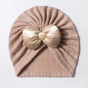 Détail du bonnet pour bébé en tricot kaki orné d'un grand nœud en satin et bouton