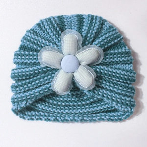Detailed knit texture of a baby striped hat with a large floral lace embellishment