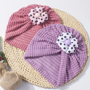 Detail of baby turban hats with polka dot flowers on a natural woven mat background