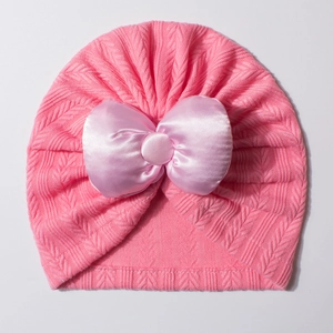 Détail du bonnet turban rose pour bébé avec un grand nœud en satin et maille chevronnée
