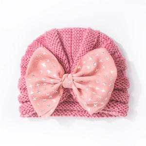 Detailed view of pink knitted baby hat featuring a large silver star print bow