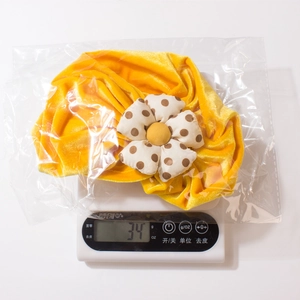 Detail shot of a yellow velvet baby turban flower hat weighing 34g on a digital scale